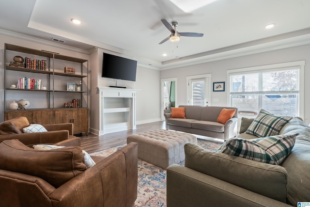 living room with dark hardwood / wood-style floors, ceiling fan, and a raised ceiling