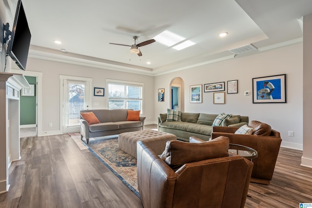 living room with ceiling fan, dark hardwood / wood-style floors, crown molding, and a tray ceiling