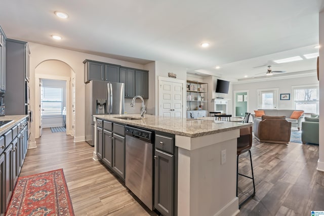 kitchen with a center island with sink, sink, ceiling fan, gray cabinets, and appliances with stainless steel finishes