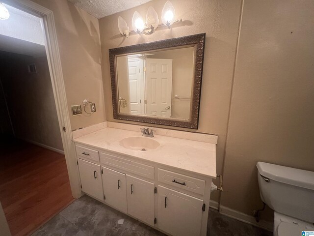 bathroom with vanity, toilet, and a textured ceiling