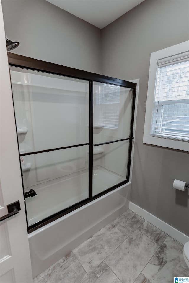 bathroom with toilet and bath / shower combo with glass door