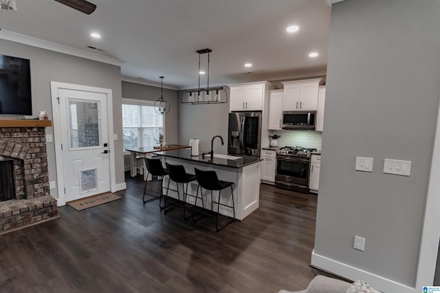 kitchen featuring a center island with sink, white cabinets, a kitchen bar, and stainless steel appliances