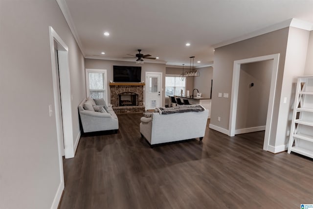 living room featuring dark hardwood / wood-style floors, a brick fireplace, ceiling fan, and ornamental molding