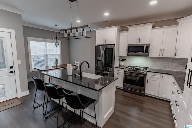 kitchen with white cabinetry, sink, stainless steel appliances, pendant lighting, and a center island with sink