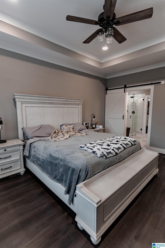 bedroom with a tray ceiling, a barn door, ceiling fan, and dark wood-type flooring