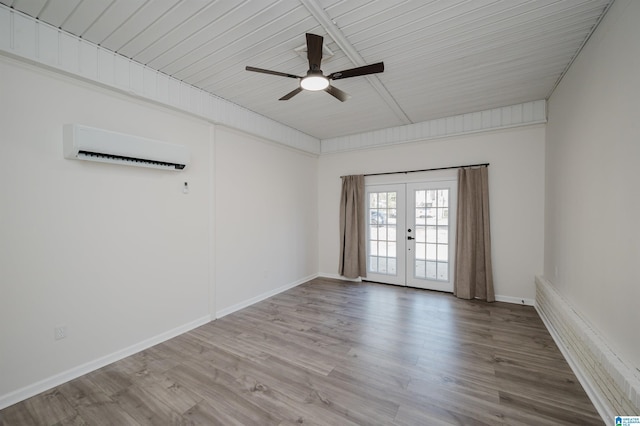 spare room with ceiling fan, a wall mounted AC, light hardwood / wood-style flooring, and french doors