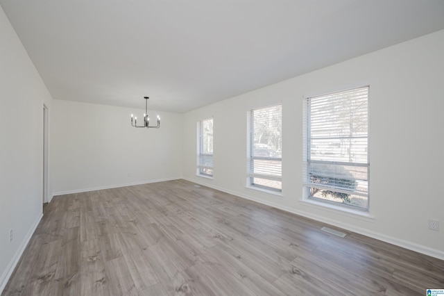 unfurnished room featuring light hardwood / wood-style floors and an inviting chandelier