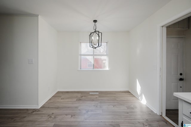 unfurnished dining area with light hardwood / wood-style flooring and a chandelier