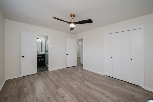 unfurnished bedroom featuring ceiling fan, a closet, connected bathroom, and light hardwood / wood-style flooring