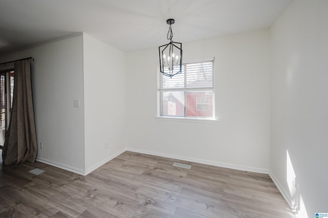 unfurnished dining area with light wood-type flooring and a chandelier