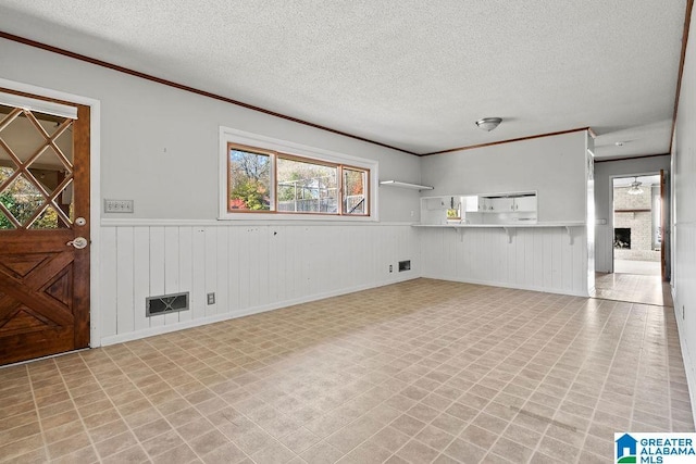 unfurnished living room with a textured ceiling, a brick fireplace, and crown molding