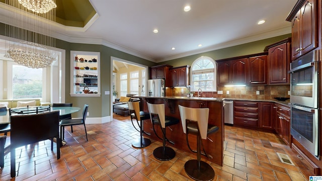 kitchen featuring sink, a breakfast bar area, a wealth of natural light, stainless steel appliances, and a chandelier