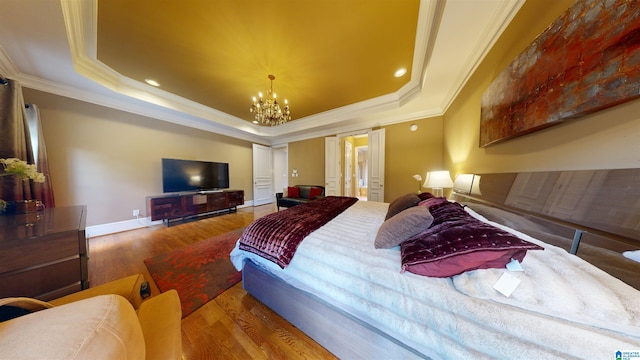 bedroom with a notable chandelier, wood-type flooring, crown molding, and a tray ceiling