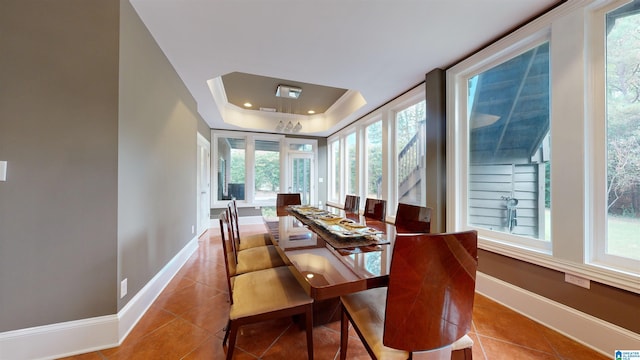 tiled dining area featuring a tray ceiling and a wealth of natural light