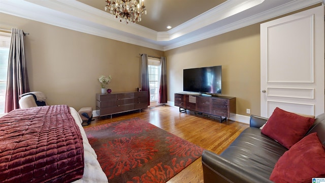 living room featuring hardwood / wood-style floors, a raised ceiling, crown molding, and an inviting chandelier