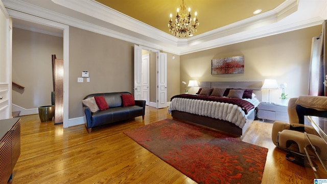 bedroom featuring hardwood / wood-style floors, a tray ceiling, crown molding, and a notable chandelier