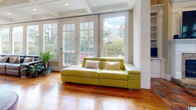 sunroom / solarium featuring a stone fireplace, beamed ceiling, and coffered ceiling