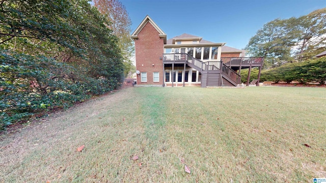 rear view of property featuring a yard, a deck, and a sunroom