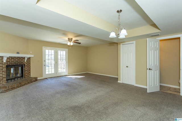 unfurnished living room with carpet, french doors, a fireplace, and ceiling fan with notable chandelier