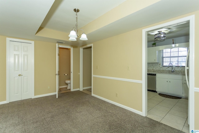 interior space featuring light colored carpet, a notable chandelier, sink, and connected bathroom