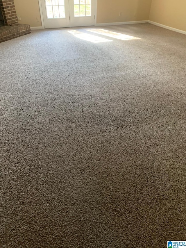 unfurnished room featuring carpet and a brick fireplace