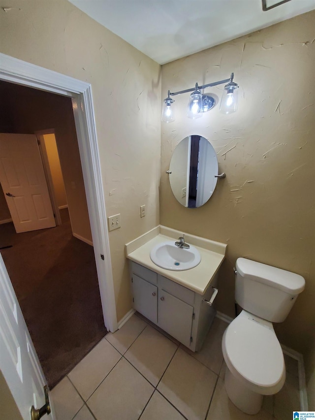 bathroom with toilet, vanity, and tile patterned flooring