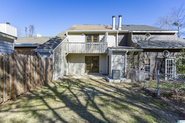 back of property with central AC unit, a balcony, and a yard