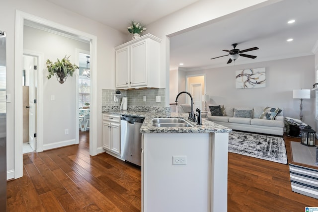 kitchen with light stone countertops, backsplash, stainless steel dishwasher, sink, and white cabinetry