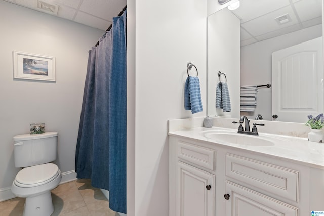 bathroom with tile patterned floors, a drop ceiling, vanity, and toilet