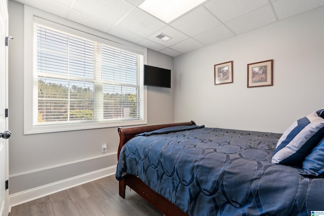 bedroom with a paneled ceiling and hardwood / wood-style floors