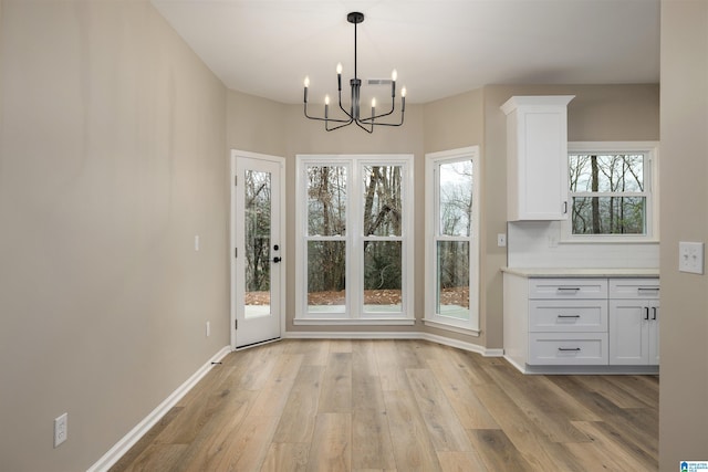 unfurnished dining area featuring light hardwood / wood-style floors and a chandelier