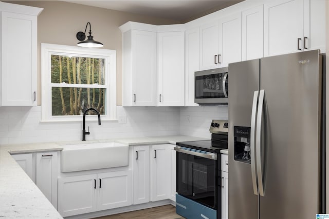 kitchen featuring white cabinets, appliances with stainless steel finishes, and light stone counters