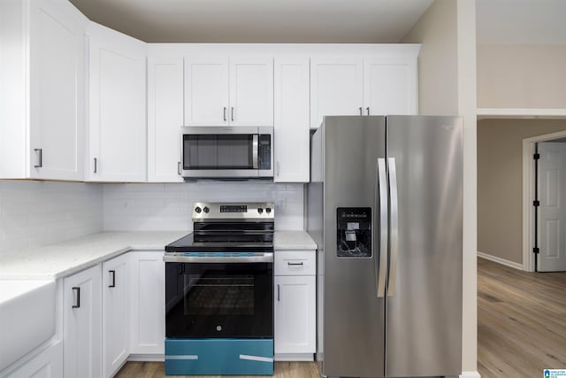 kitchen featuring white cabinets, light stone counters, appliances with stainless steel finishes, and tasteful backsplash