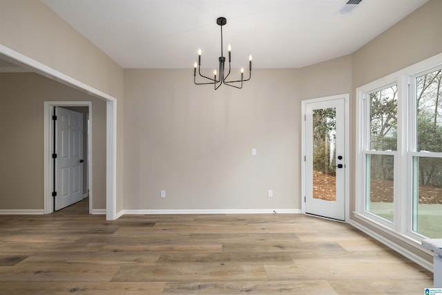 unfurnished dining area with light hardwood / wood-style floors and an inviting chandelier