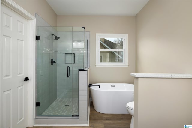 bathroom featuring toilet, hardwood / wood-style floors, and shower with separate bathtub