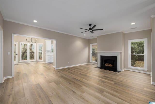 unfurnished living room featuring crown molding, light hardwood / wood-style floors, and ceiling fan with notable chandelier