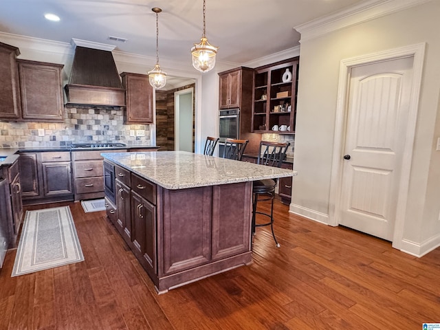 kitchen featuring a center island, premium range hood, decorative light fixtures, a breakfast bar, and appliances with stainless steel finishes