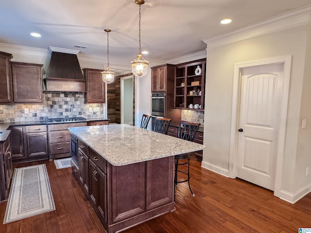 kitchen featuring a kitchen bar, custom range hood, dark brown cabinets, decorative light fixtures, and a kitchen island