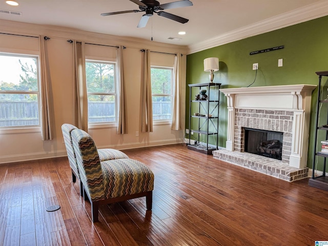 sitting room featuring crown molding, ceiling fan, wood-type flooring, and a brick fireplace