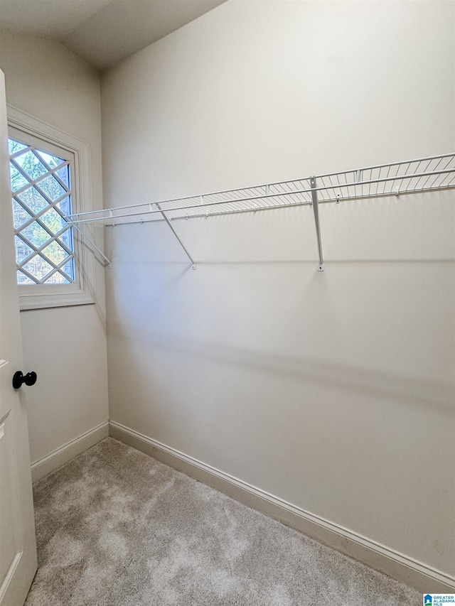 spacious closet featuring light colored carpet and lofted ceiling