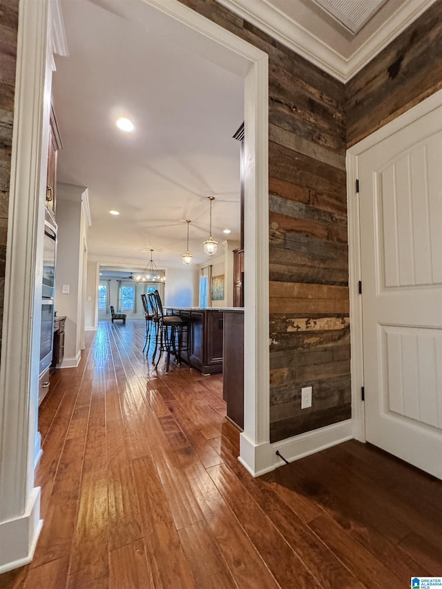 entryway with crown molding, dark wood-type flooring, and wood walls