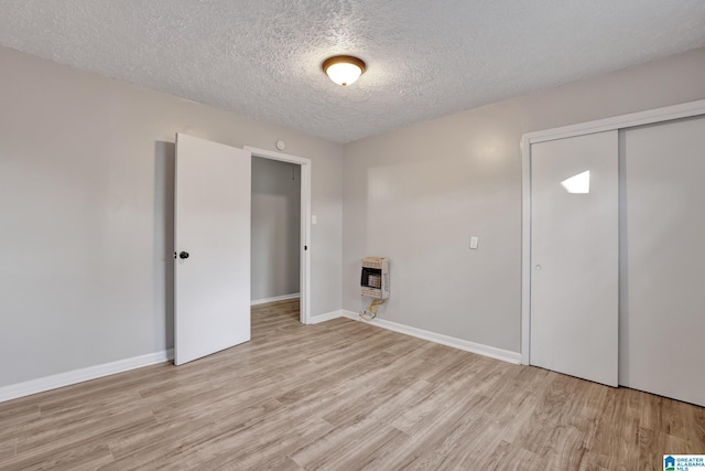 washroom featuring light wood-type flooring, a textured ceiling, and heating unit