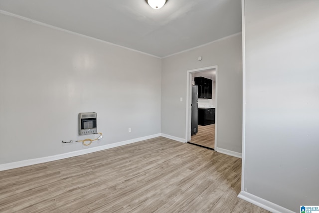 spare room featuring heating unit and light hardwood / wood-style floors