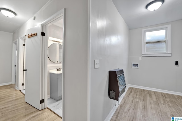 clothes washing area with heating unit and light hardwood / wood-style floors