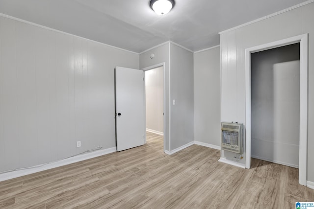 unfurnished bedroom with heating unit, light hardwood / wood-style floors, and ornamental molding