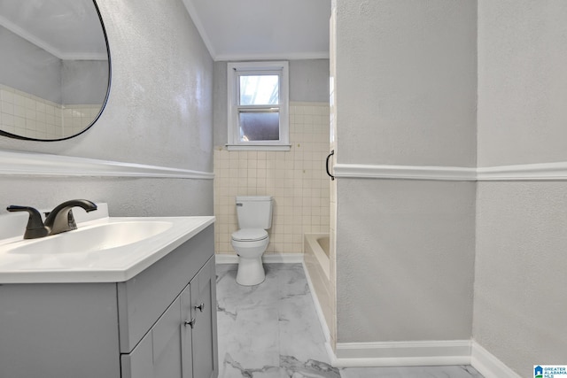 bathroom with vanity, toilet, tile walls, and ornamental molding