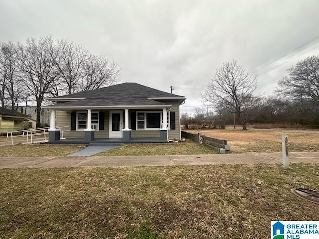 bungalow-style home featuring covered porch and a front lawn