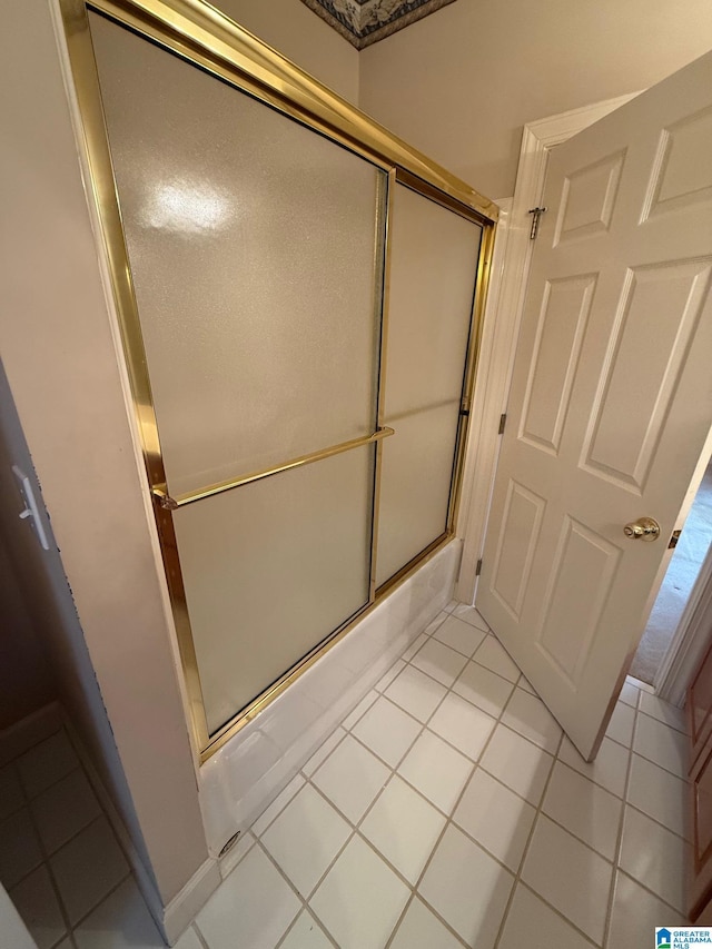 bathroom featuring tile patterned flooring and bath / shower combo with glass door