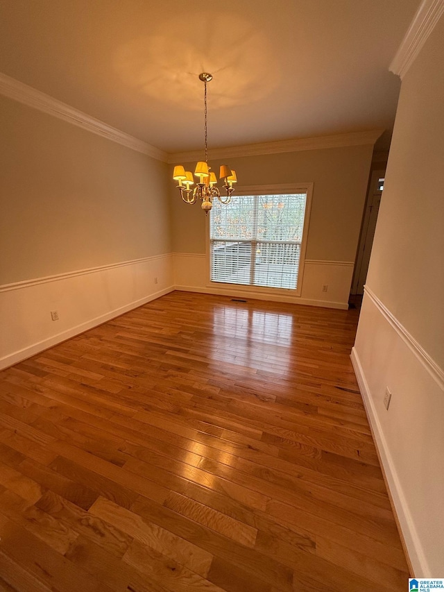 empty room with a chandelier, dark hardwood / wood-style floors, and ornamental molding