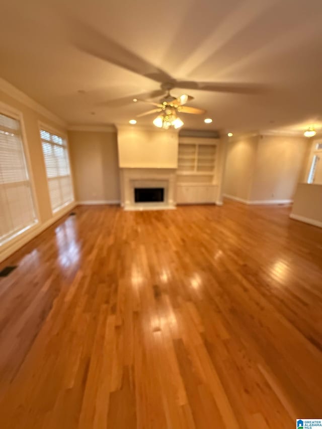 unfurnished living room with hardwood / wood-style flooring, ceiling fan, and ornamental molding